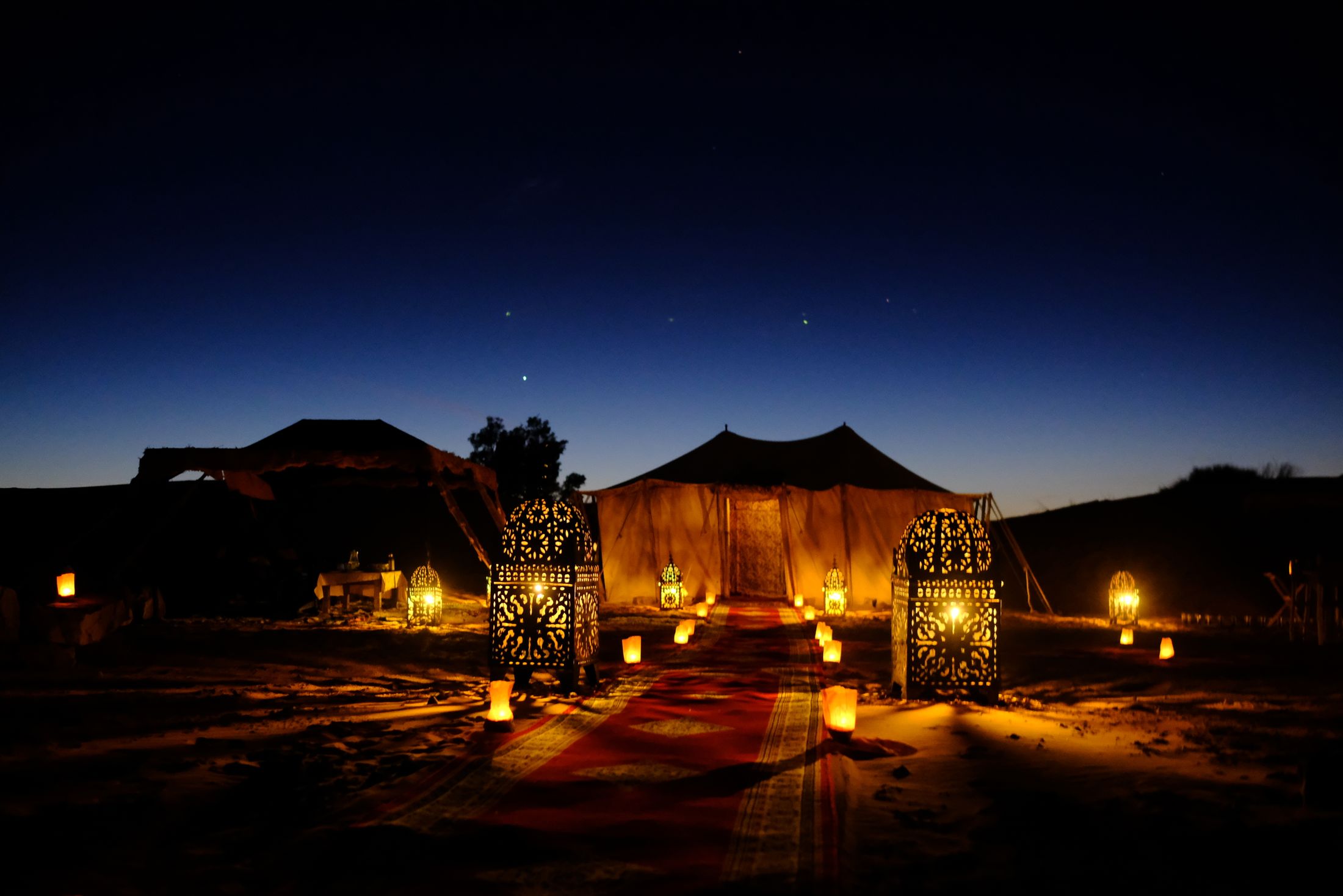 Warm lantern light inside an Egyptian desert camp at twilight